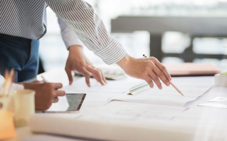 Hands with blueprint and tablet for energy project
