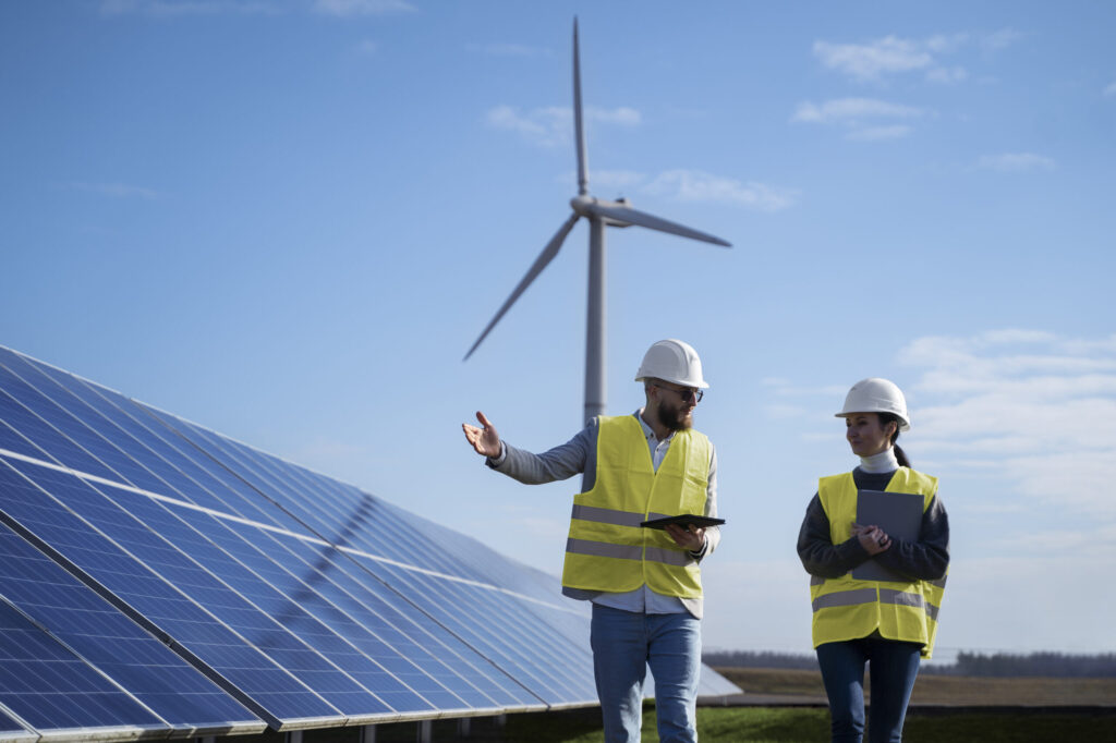 Two people walking near solar and wind installations