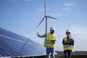 Two people walking near solar and wind installations