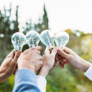 Hands holding lightbulbs outdoors