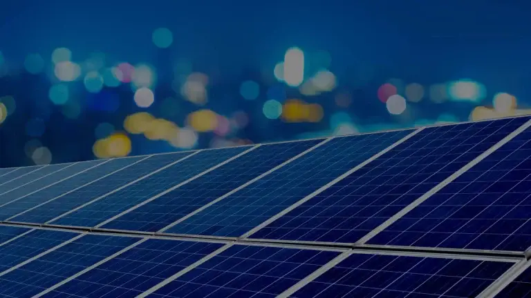 Solar panels with blurred city lights at night in background