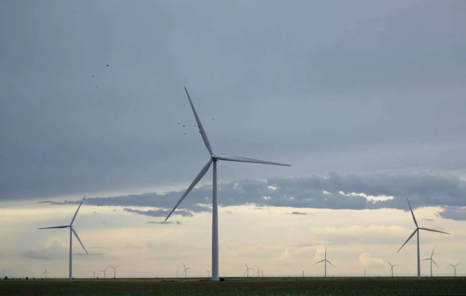 Landscape view of onshore wind turbines operating under variable cloud cover, representing renewable energy weather dependency.